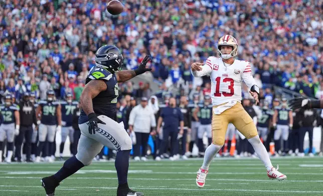 San Francisco 49ers quarterback Brock Purdy (13) throws a 2-point conversion pass as Seattle Seahawks defensive tackle Byron Murphy II (91) tries to apply pressure during the second half of an NFL football game Sunday, Oct. 11, 2026, in Seattle. (AP Photo/Lindsey Wasson)