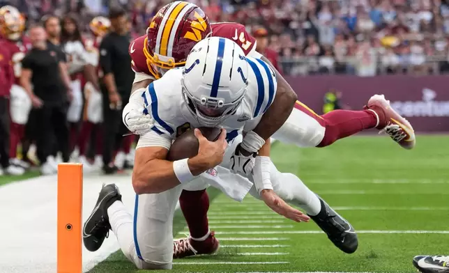 Indianapolis Colts quarterback Daniel Jones (17) gets past Washington Commanders cornerback Amik Robertson (2) to score a touchdown during an NFL football game in London, Sunday, Oct. 4, 2026. (AP Photo/David J. Phillip)