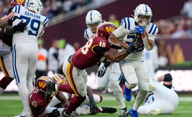 Indianapolis Colts running back Jonathan Taylor (28) is tackled by Washington Commanders linebacker Joshua Josephs (48) during an NFL football game in London, Sunday, Oct. 4, 2026. (AP Photo/David J. Phillip)