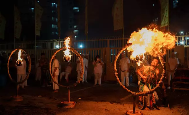 A devotee breathes fire through a hoop during the Nine Emperor Gods Festival at Bei Tian Gong Temple in Jinjang, Kuala Lumpur, Malaysia, Thursday, Oct. 15, 2026. (AP Photo/Vincent Thian)