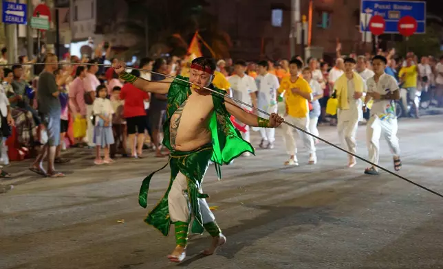 A devout participating as a spirit medium walks with a metal rod piercing his cheeks on the final day of the Nine Emperor Gods Festival on Penang island, Malaysia, Sunday, Oct. 18, 2026. (AP Photo/Vincent Thian)