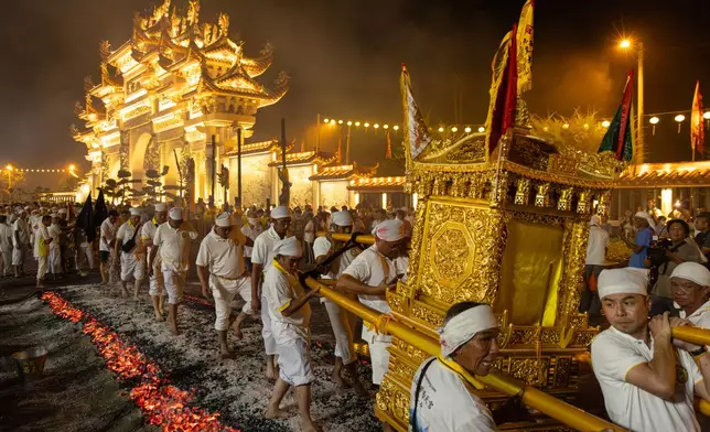 Devotees carry a Taoist sedan chair over burning charcoal during celebrations of the Nine Emperor Gods Festival in Kuala Pilah, Malaysia on Saturday, Oct. 17, 2026. (AP Photo/Anton L. Delgado)