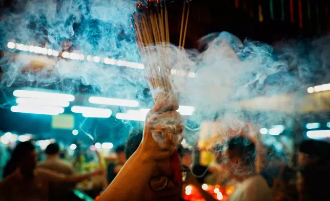 A devotee holds burning incense sticks while praying at the Nine Emperor Gods Temple in Ampang, Malaysia, Friday, Oct. 16, 2026. (AP Photo/Vincent Thian)