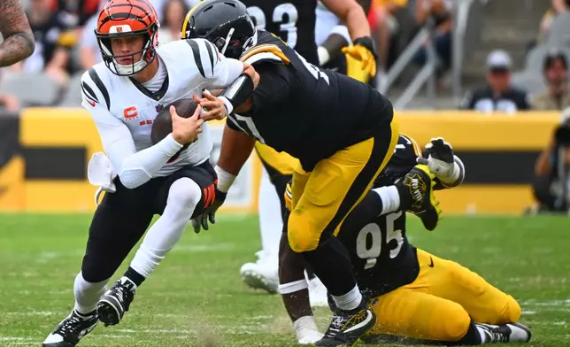 Cincinnati Bengals quarterback Joe Burrow, left, runs with the ball during the second half of an NFL football game against the Pittsburgh Steelersin Pittsburgh, Sunday, Sept. 27, 2026. (AP Photo/Justin Berl)