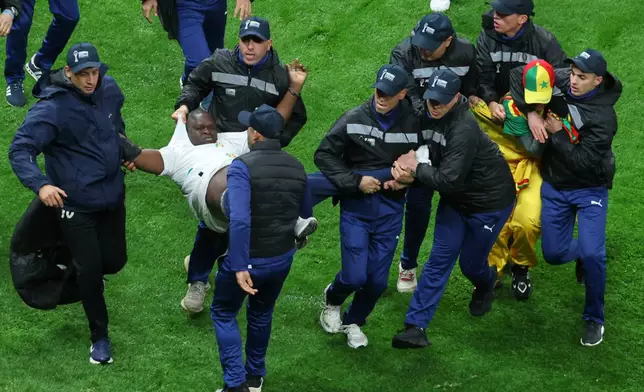 FILE - Senegal supporters are taken from the stadium by security officers after a controversial penalty was awarded to Morocco late on during the Africa Cup of Nations final soccer match between Senegal and Morocco in Rabat, Morocco, Jan. 18, 2026. (AP Photo/Youssef Loulidi, File)