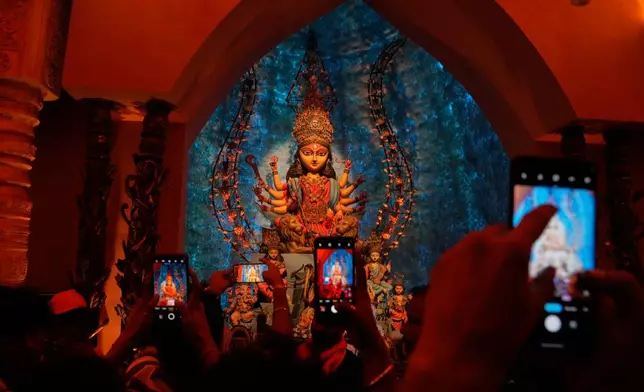 FILE - People take photos of an idol of Hindu goddess Durga at a makeshift worship venue on the last day of the festival Durga Puja, in Kolkata, India, Oct. 21, 2026. (AP Photo/Bikas Das, File)