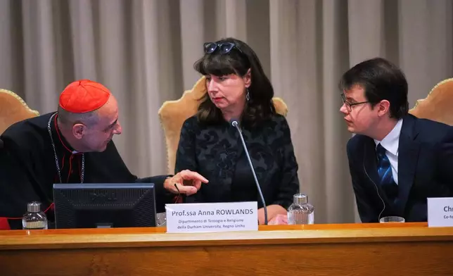 FILE - From left, Cardinal Víctor Manuel Fernández, prefect of the Dicastery for the Doctrine of the Faith, talks with theologian Anna Rowlands, and Anthropic co-founder Christopher Olah during the presentation of Pope Leo XIV's first encyclical, "Magnifica humanitas: On Safeguarding the Human Person in the Time of Artificial Intelligence," at the Vatican, May 25, 2026. (AP Photo/Alessandra Tarantino, File)