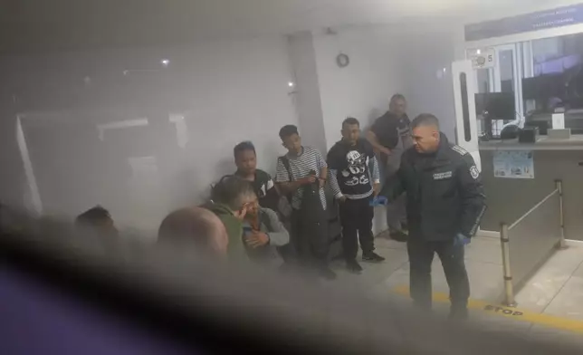 Border police officer talks to saved crew members of the Liberian-flagged container ship Contship Jet, which was attacked by drones, in Varna, Bulgaria, late Wednesday, Oct. 28, 2026. (AP Photo/Petko Momchilov)