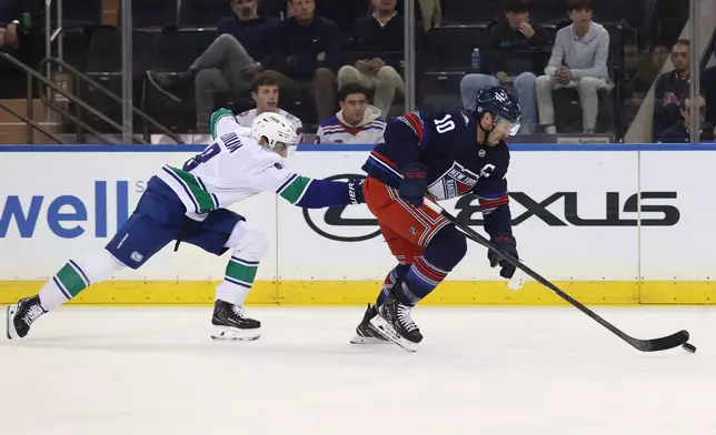 New York Rangers J.T. Miller (10) and Vancouver Canucks' Zeev Buium (8) compete for the puck during the first period of an NHL hockey game Sunday, Oct. 11, 2026, in New York. (AP Photo/Pamela Smith)