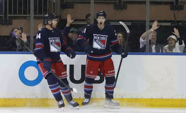 New York Rangers' Vladislav Gavrikov, left, and Tye Kartye, right, react after Kartye scored during the first period of an NHL hockey game against the Vancouver Canucks Sunday, Oct. 11, 2026, in New York. (AP Photo/Pamela Smith)