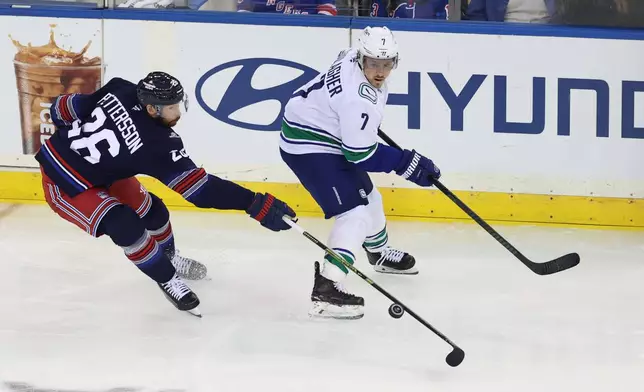 New York Rangers' Marcus Pettersson, left, skates with the puck against Vancouver Canucks' Brendan Gallagher, right, during the third period of an NHL hockey game Sunday, Oct. 11, 2026, in New York. (AP Photo/Pamela Smith)