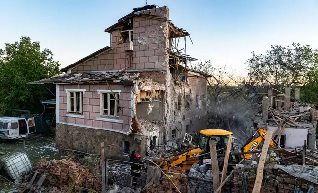 Rescue workers clear the rubble of a residential house destroyed in a Russian air strike on Kharkiv, Ukraine, Friday, Oct. 2, 2026. (AP Photo/Andrii Marienko)