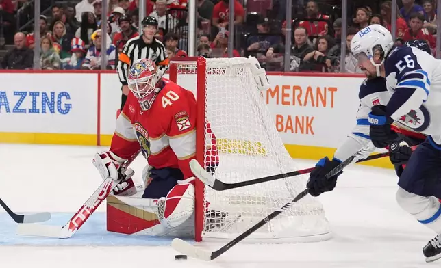 Florida Panthers goaltender Akira Schmid (40) eyes the puck as Winnipeg Jets center Mark Scheifele (55) looks for an opening during the first period of an NHL hockey game, Friday, Oct. 30, 2026, in Sunrise, Fla. (AP Photo/Rebecca Blackwell)