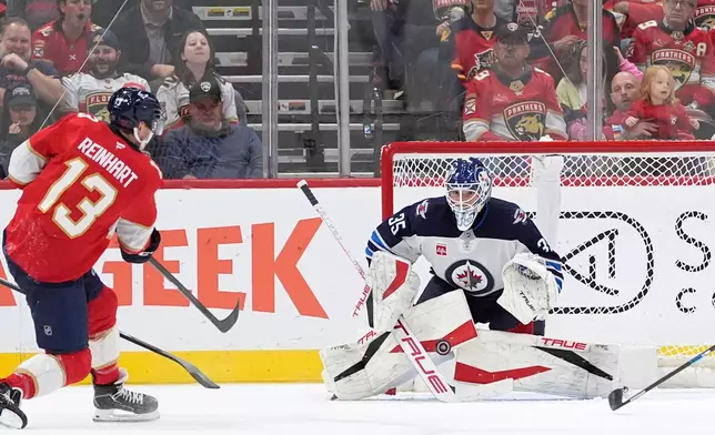 Winnipeg Jets goaltender Nico Daws (35) deflects a shot from Florida Panthers center Sam Reinhart (13) during the first period of an NHL hockey game, Friday, Oct. 30, 2026, in Sunrise, Fla. (AP Photo/Rebecca Blackwell)
