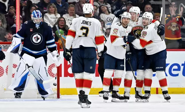 Florida Panthers' Sam Reinhart (13) celebrates his goal on Winnipeg Jets goaltender Clay Stevenson (33) with Brady Tkachuk (8), second from right, Seth Jones (3) and Matthew Tkachuk (19), right, during the second period of an NHL hockey game in Winnipeg, Manitoba, Tuesday, Oct. 27, 2026. (Fred Greenslade/The Canadian Press via AP)
