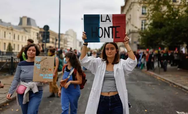 A student holds a board reading 'Shame' as she marches to protest against under-resourced schools in Rennes, France, Tuesday, Oct. 13, 2026. (AP Photo/Jeremias Gonzalez)