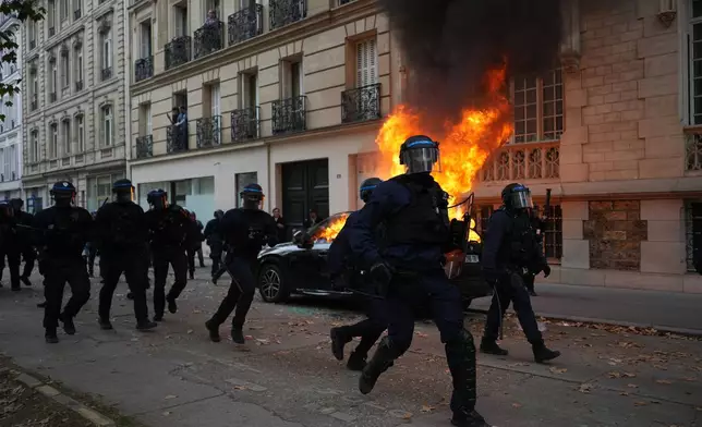 Police run towards students during a march to protest against under-resourced schools in Paris, Tuesday Oct. 13, 2026. (AP Photo/Thibault Camus)