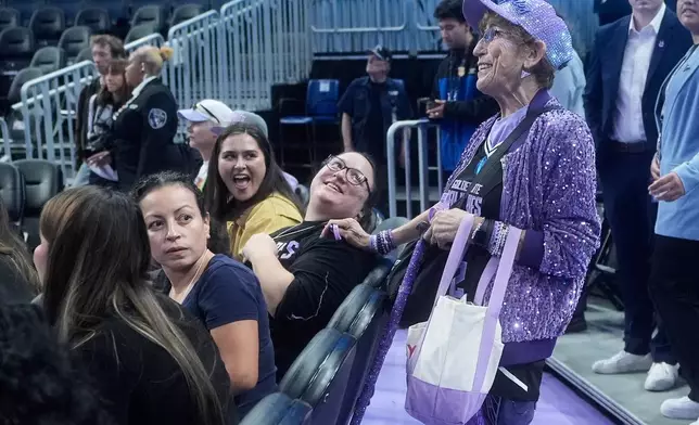 Golden State Valkyries fan Cynthia Cheak, right, hands out wristbands to fans before an WNBA basketball game between the Valkyries and Seattle Storm in San Francisco, Sept. 19, 2026. (AP Photo/Jeff Chiu)