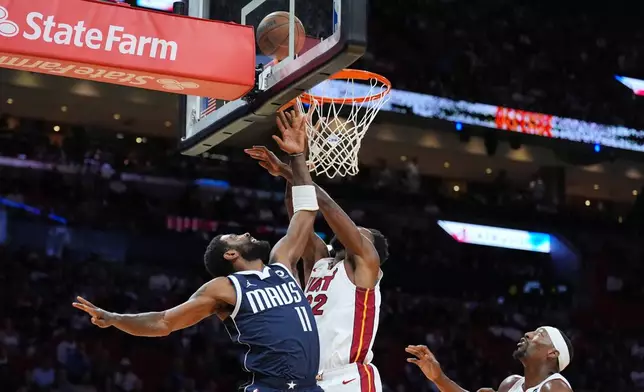 Dallas Mavericks guard Kyrie Irving (11) shoots under pressure from Miami Heat forward Andrew Wiggins (22) as center Bam Adebayo looks on during the first half of an NBA basketball game, Monday, Oct. 26, 2026, in Miami. (AP Photo/Rebecca Blackwell)