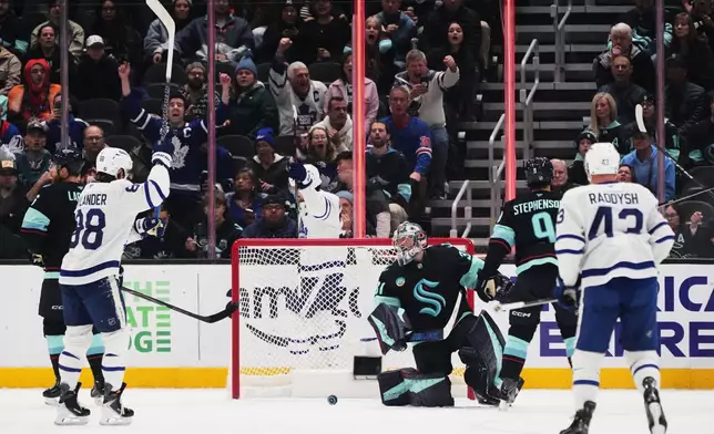 Toronto Maple Leafs players, including right wing William Nylander (88) celebrate a goal by teammate Gavin McKenna against Seattle Kraken goaltender Philipp Grubauer, center, during the first period of an NHL hockey game, Wednesday, Oct. 28, 2026, in Seattle. (AP Photo/Lindsey Wasson)