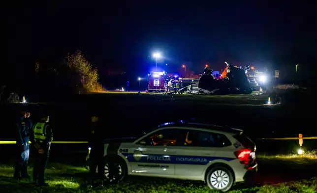 First responders stand next to the wreckage of an Italian CH-47 Chinook helicopter crashed in Brcko, Bosnia, Thursday, Oct. 29, 2026. (AP Photo/Predrag Simic)