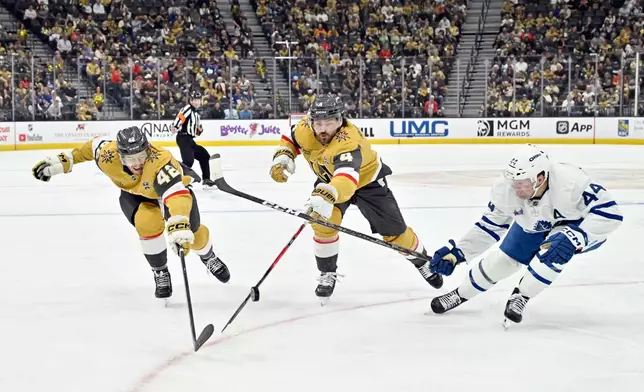 Vegas Golden Knights' Braeden Bowman (42), Knights' Rasmus Andersson (4) and Toronto Maple Leafs' Morgan Rielly (44) chase the puck during the second period of an NHL hockey game Thursday, Oct. 8, 2026, in Las Vegas. (AP Photo/David Becker)