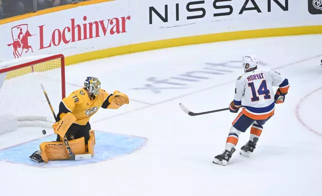New York Islanders center Bo Horvat (14) scores on Nashville Predators goaltender Juuse Saros (74) during a shootout in an NHL hockey game Tuesday, Oct. 27, 2026, in Nashville, Tenn. (AP Photo/John Amis)