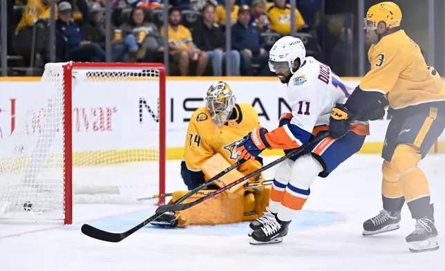 New York Islanders left wing Anthony Duclair (11) scores on Nashville Predators goaltender Juuse Saros, left, and defenseman Jayden Struble (3) during the first period of an NHL hockey game Tuesday, Oct. 27, 2026, in Nashville, Tenn. (AP Photo/John Amis)