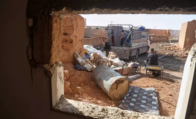Returning residents unload belongings from a truck amid damaged buildings in Al-Arisha, in Syria's Ras al-Ayn countryside, Tuesday, Oct. 13, 2026, seven years after a Turkish military offensive backed by allied Syrian factions forced them to flee. (AP Photo/Baderkhan Ahmad)