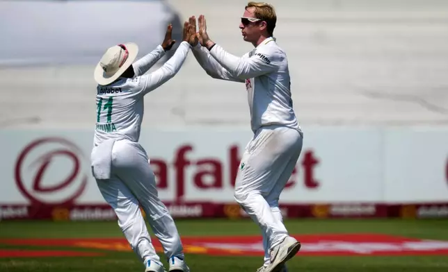 South Africa's Simon Harmer, right, celebrates a wicket with his captain Temba Bavuma on day four of the first cricket test match between South Africa and Australia, in Durban, South Africa, Monday, Oct. 12, 2026. (AP Photo/Themba Hadebe)