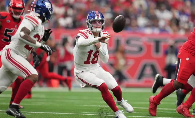 New York Giants quarterback J.J. McCarthy (18) tosses a shuttle pass to running back Tyrone Tracy Jr., front left, during the first half of an NFL football game against the Houston Texans in Houston, Sunday, Oct. 25, 2026. (AP Photo/Eric Smith)