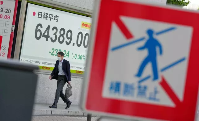A person walks in front of an electronic stock board showing Japan's Nikkei index at a securities firm Thursday, Oct. 22, 2026, in Tokyo. (AP Photo/Eugene Hoshiko)