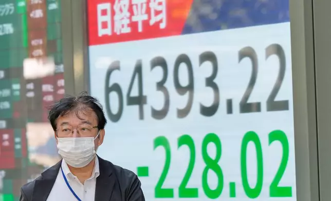 A person walks in front of an electronic stock board showing Japan's Nikkei index at a securities firm Thursday, Oct. 22, 2026, in Tokyo. (AP Photo/Eugene Hoshiko)