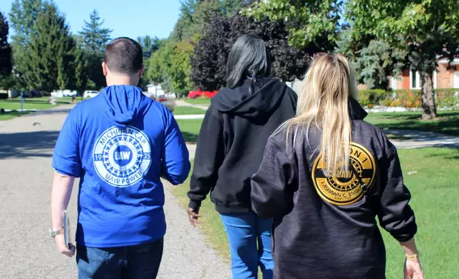 United Auto Workers union canvassers JJ Jewell, from left, LaShawn Barnett and Kim Avouris check canvassing routes on their phones in Shelby Township, Mich., Saturday, Sept. 26, 2026. (AP Photo/Jacqueline GaNun)