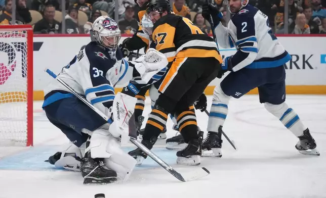 Pittsburgh Penguins' Rickard Rakell, center, cannot get his stick on a rebound off Winnipeg Jets goaltender Clay Stevenson (33) during the second period of an NHL hockey game in Pittsburgh, Monday, Oct. 5, 2026. (AP Photo/Gene J. Puskar)