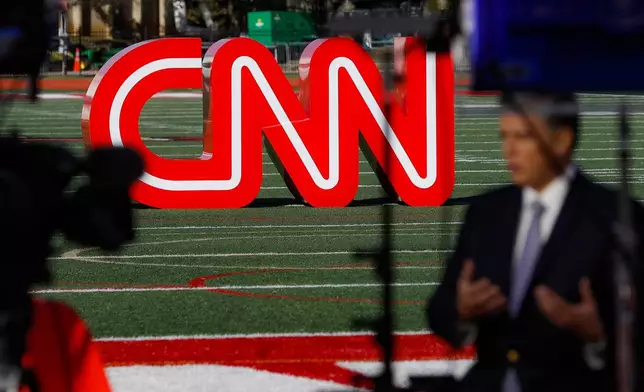 FILE - A journalist records video near a CNN sign on an athletic field outside the Clements Recreation Center where the CNN/New York Times will host the Democratic presidential primary debate at Otterbein University, Monday, Oct. 14, 2019, in Westerville, Ohio. (AP Photo/John Minchillo, File)