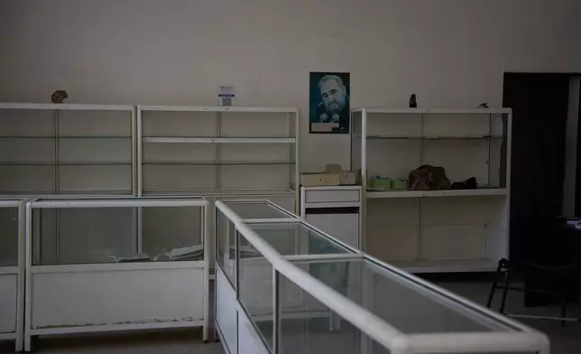 A poster of Fidel Castro hangs on the wall, flanked by empty shelves, at a state-run pharmacy in Havana, Cuba, Thursday, Oct. 8, 2026. (AP Photo/Ramon Espinosa)