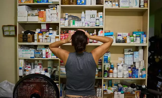 Laura Mendoza, who runs the “Medicine Is Not for Sale” community project, stands in front of a shelf stocked with medicine donated by humanitarian groups for free distribution in Havana, Cuba, Thursday, Oct. 8, 2026. (AP Photo/Ramon Espinosa)