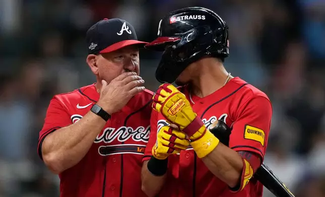Atlanta Braves manager Walt Weiss, left, talks with Mauricio Dubón, right, against the Philadelphia Phillies in the first inning during Game 3 of baseball's NL Wild Card Series, Thursday, Oct. 1, 2026, in Atlanta. (AP Photo/Brynn Anderson)