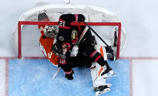 Ottawa Senators' Shane Pinto (12) collides with Philadelphia Flyers' Dan Vladar (80) during the third period of an NHL hockey game Saturday, Oct. 17, 2026, in Philadelphia. (AP Photo/Matt Slocum)