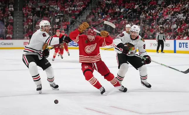 Detroit Red Wings left wing Lucas Raymond (23) chases the puck as Chicago Blackhawks defenseman Sam Rinzel (6) and Ian Cole (28) defendin the first period of an NHL hockey game Thursday, Oct. 29, 2026, in Detroit. (AP Photo/Paul Sancya)