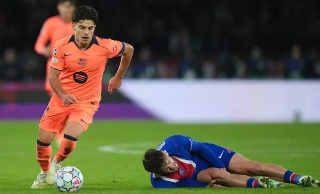 PSG's Khvicha Kvaratskhelia grimaces in pain after a challenges for the ball with Barcelona's Xavi Espart, left, during the Champions League opening phase soccer match between Paris Saint-Germain and FC Barcelona in Paris, Tuesday, Oct. 20, 2026. (AP Photo/Thibault Camus)