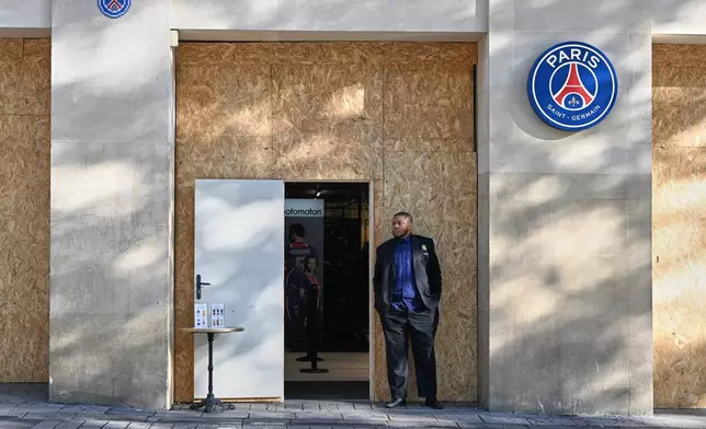 A man stands in front of a barricaded shop of the soccer team Paris Saint-Germain before protests over living costs and education in Paris, France, Saturday, Oct. 31, 2026. (AP Photo/Emma Da Silva)