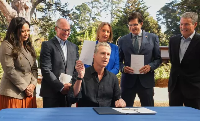 California Gov. Gavin Newsom displays one of the conservation bills he signed during a visit to the California Academy of Sciences in San Francisco, Tuesday, Sept. 29, 2026. (AP Photo/Rich Pedroncelli)