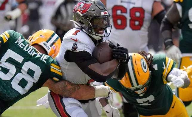 Tampa Bay Buccaneers running back Kenny Gainwell (1) is tackles by Green Bay Packers linebacker Isaiah McDuffie (58) and safety Javon Bullard (7) during the second half of an NFL football game in Tampa, Fla., Sunday, Oct. 4, 2026. (AP Photo/Chris O'Meara)