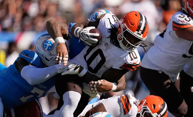 Cleveland Browns running back Quinshon Judkins (10) is tackled by Tennessee Titans defensive ends Oluwafemi Oladejo (7) and Keldric Faulk (15), obscured, during the first half of an NFL football game in Nashville, Tenn., Sunday, Oct. 25, 2026. (AP Photo/George Walker IV)