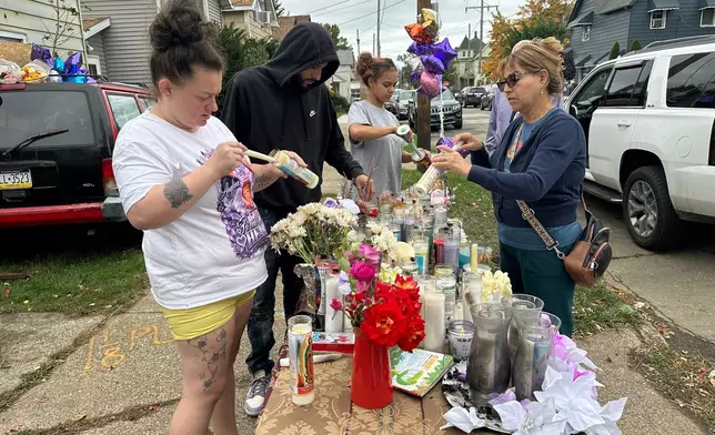 People gather at a memorial in Erie, Pa., Sunday, Oct. 11, 2026, outside the home where authorities say a gunman killed several people before killing himself on Oct. 9. (AP Photo/Ted Shaffrey)