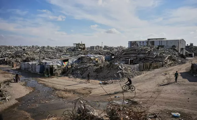 Palestinians walk along a street surrounded by buildings destroyed in Israeli military strikes during the Israel-Hamas war in Gaza City, Tuesday, Oct. 6, 2026. (AP Photo/Abdel Kareem Hana)