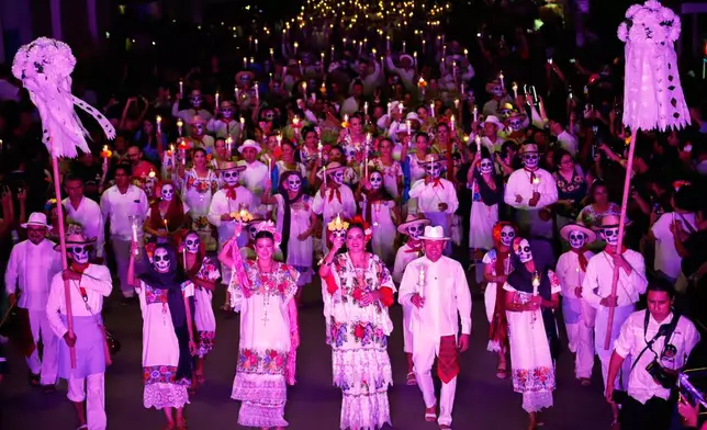People in traditional dress, some with skull makeup, march during the Paseo de las Animas parade as part of the Day of the Dead celebrations in Merida, Mexico, Friday, Oct. 30, 2026. (AP Photo/Martin Zetina)