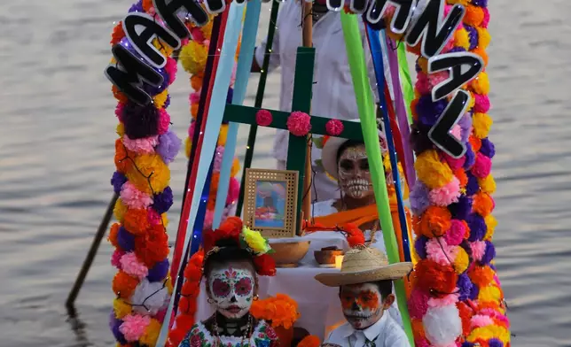 Children dressed as Mexico's iconic "Catrinas" sit aboard a boat decorated as a floating altar during Day of the Dead celebrations in Sisal, Mexico, Friday, Oct. 30, 2026. (AP Photo/Martin Zetina)